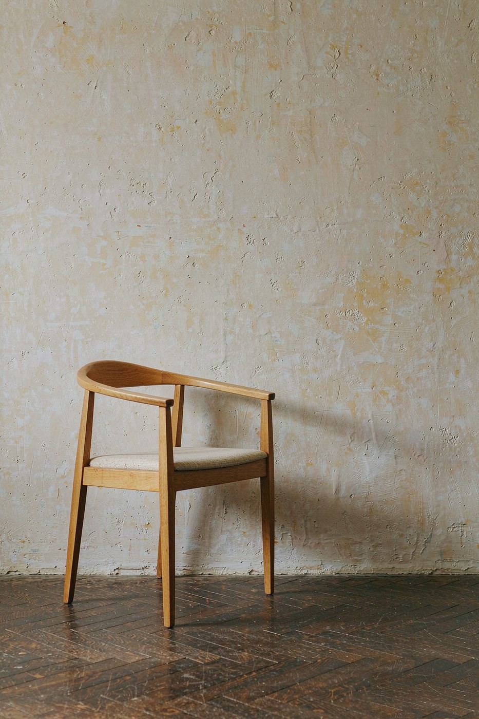Minimal wooden chair against a plaster wall
