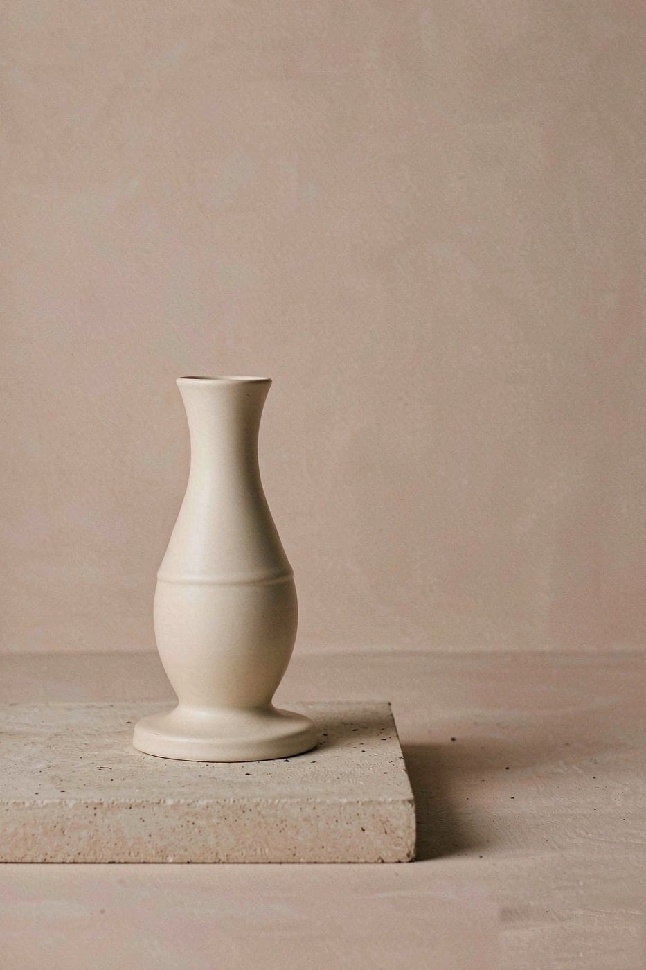 Matte cream ceramic vessel on a stone plinth